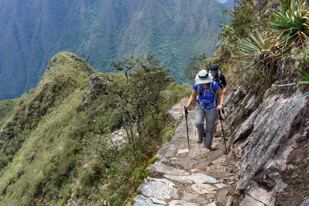 A walker on the stone path of the Inca Trail high above the valley